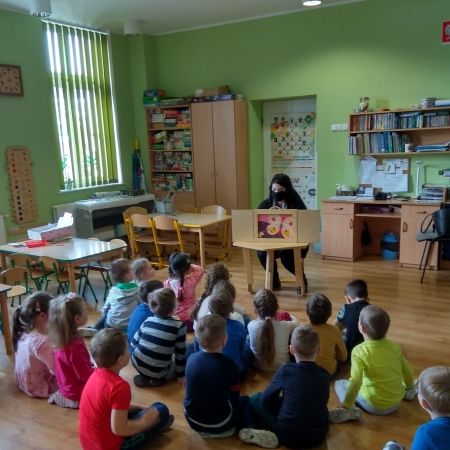 Bibliotekarka czyta dzieciom przy pomocy teatrzyku Kamishibai.
