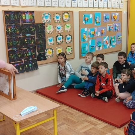 Fotografia kolorowa. Bibliotekarka przedstawia dzieciom historię za pomocą drewnianego teatrzyku. 
