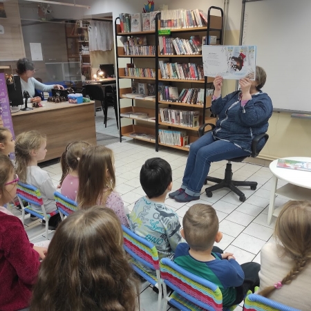 Fotografia kolorowa. Przedszkolaki słuchają opowieści bibliotekarki. 