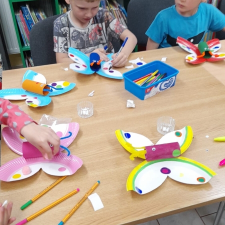 Fotografia kolorowa. Dzieci wykonują kolorowe motyle.