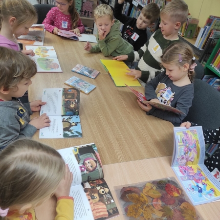 Fotografia kolorowa.  Przedszkolaki przeglądają książki. 