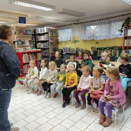 Fotografia kolorowa.  Przedszkolaki słuchają bibliotekarki. 