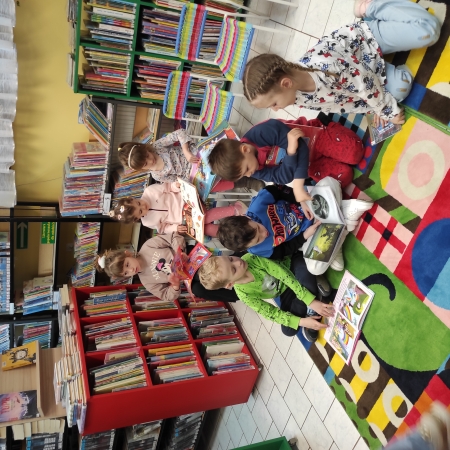 Fotografia kolorowa. Dzieci czytają książki w bibliotece.