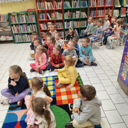  Fotografia kolorowa. Zdjęcie grupowe przedszkolaków w pomieszczeniu biblioteki.