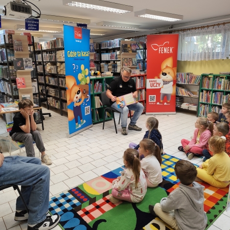  Fotografia kolorowa.  Zdjęcie grupowe przedszkolaków w pomieszczeniu biblioteki.