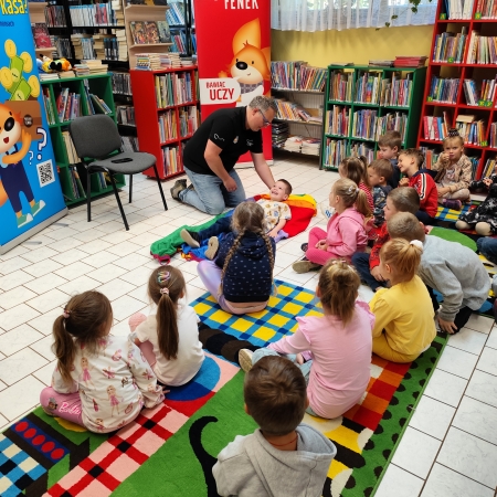  Fotografia kolorowa.  Zdjęcie grupowe przedszkolaków w pomieszczeniu biblioteki.