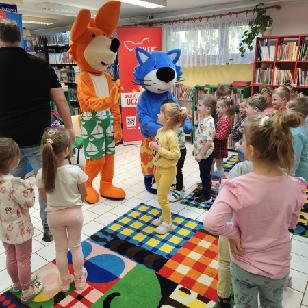  Fotografia kolorowa. Zdjęcie grupowe przedszkolaków w pomieszczeniu biblioteki.