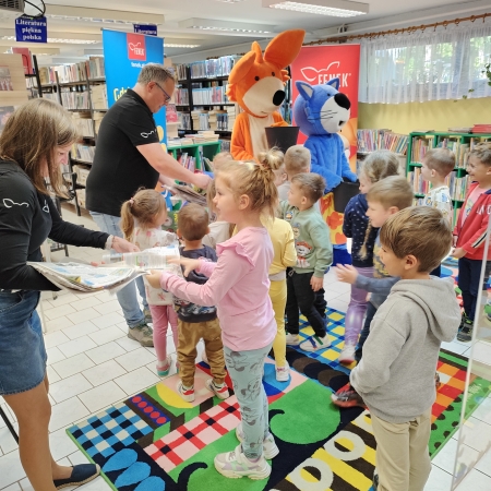  Fotografia kolorowa. Zdjęcie grupowe przedszkolaków w pomieszczeniu biblioteki.