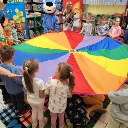  Fotografia kolorowa. Zdjęcie grupowe przedszkolaków w pomieszczeniu biblioteki.