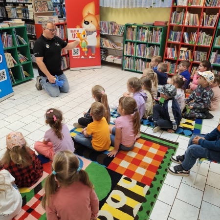  Fotografia kolorowa.  Zdjęcie grupowe przedszkolaków w pomieszczeniu biblioteki.