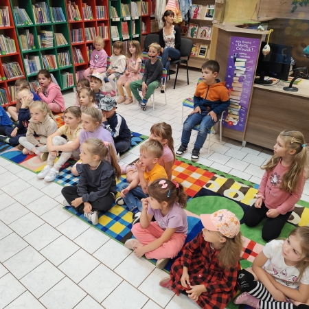  Fotografia kolorowa. Zdjęcie grupowe przedszkolaków w pomieszczeniu biblioteki.