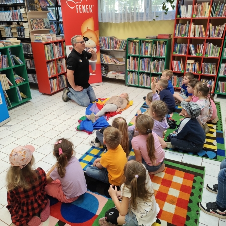  Fotografia kolorowa. Zdjęcie grupowe przedszkolaków w pomieszczeniu biblioteki.