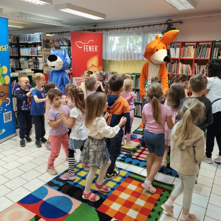  Fotografia kolorowa. Zdjęcie grupowe przedszkolaków w pomieszczeniu biblioteki.