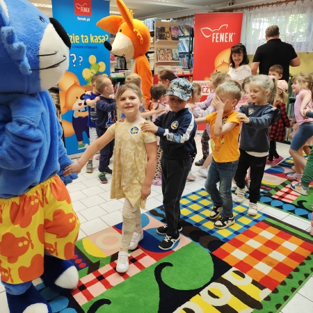  Fotografia kolorowa. Zdjęcie grupowe przedszkolaków w pomieszczeniu biblioteki.