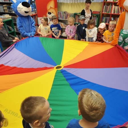  Fotografia kolorowa. Zdjęcie grupowe przedszkolaków w pomieszczeniu biblioteki.