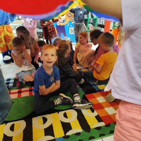  Fotografia kolorowa. Zdjęcie grupowe przedszkolaków w pomieszczeniu biblioteki.