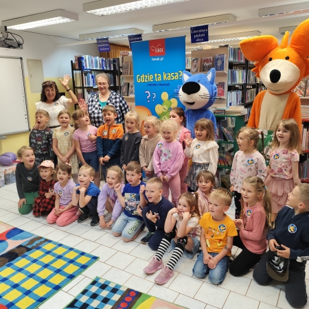  Fotografia kolorowa. Zdjęcie grupowe przedszkolaków w pomieszczeniu biblioteki.