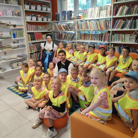 Fotografia kolorowa. Zdjęcie grupowe we wnętrzu biblioteki w Brennej. 