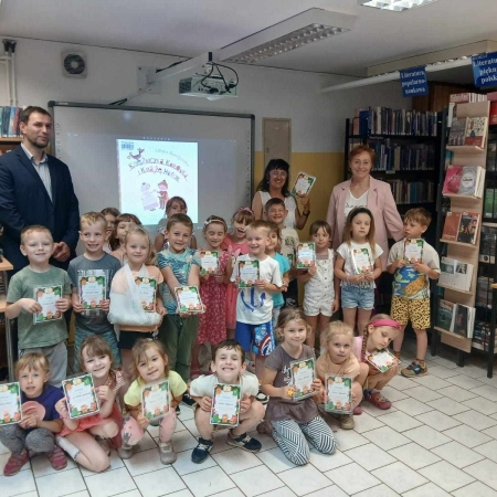 Fotografia kolorowa. Zdjęcie grupowe we wnętrzu biblioteki w Górkach Małych. 