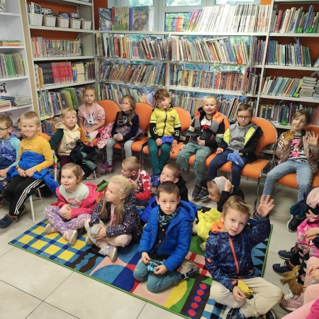 Fotografia kolorowa. Zdjęcie grupowe we wnętrzu biblioteki.