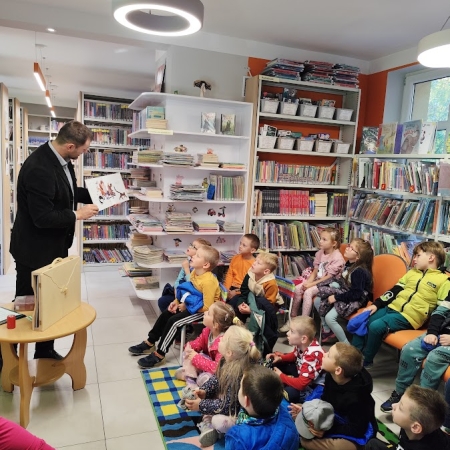 Fotografia kolorowa. Zdjęcie grupowe we wnętrzu biblioteki.