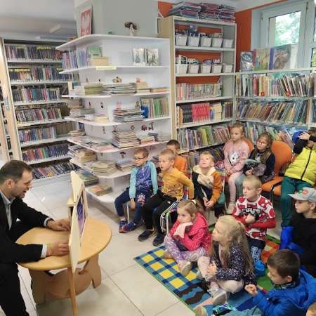 Fotografia kolorowa. Zdjęcie grupowe we wnętrzu biblioteki.