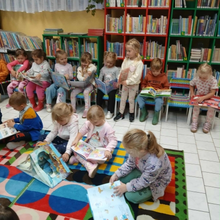 Fotografia kolorowa. Dzieci przeglądają książki w bibliotece.