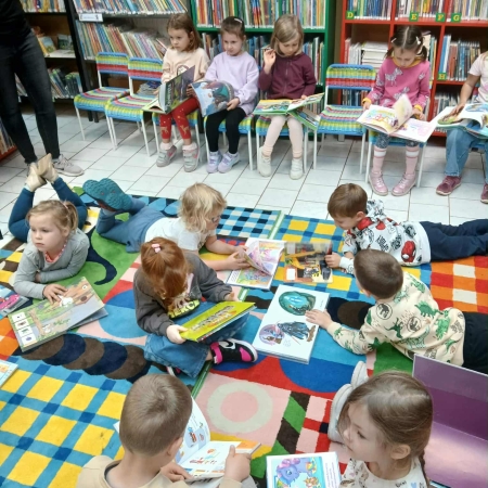 Fotografia kolorowa. Dzieci przeglądają książki w bibliotece.