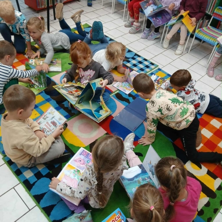 Fotografia kolorowa. Dzieci przeglądają książki w bibliotece.