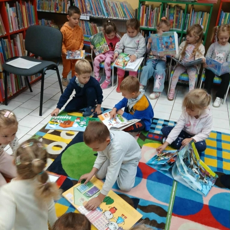 Fotografia kolorowa. Dzieci przeglądają książki w bibliotece.