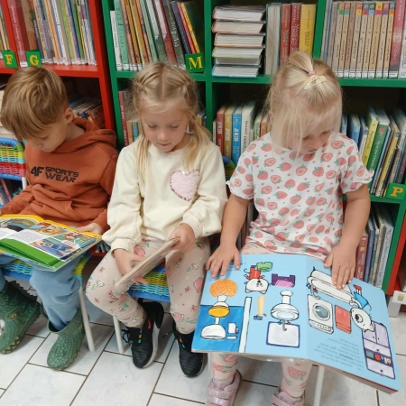 Fotografia kolorowa. Dzieci przeglądają książki w bibliotece.