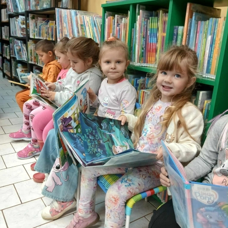 Fotografia kolorowa. Dzieci przeglądają książki w bibliotece.