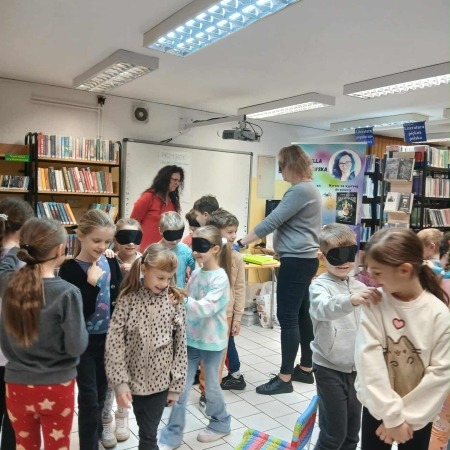 Fotografia kolorowa. Zdjęcie grupowe we wnętrzu biblioteki w Górkach Małych.