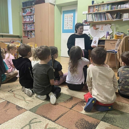 Fotografia kolorowa. Bibliotekarka robi dzieciom misiowy quiz. 