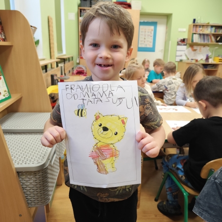 Fotografia kolorowa. Chłopiec i jego praca plastyczna.