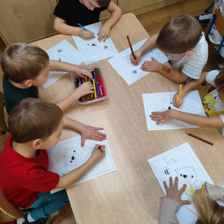 Fotografia kolorowa. Dzieci i ich misiowe prace plastyczne.