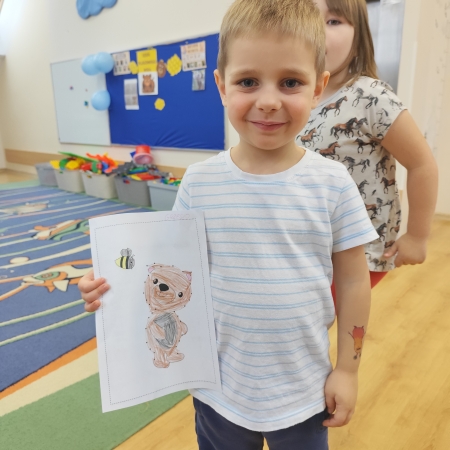 Fotografia kolorowa. Chłopiec i jego praca plastyczna.