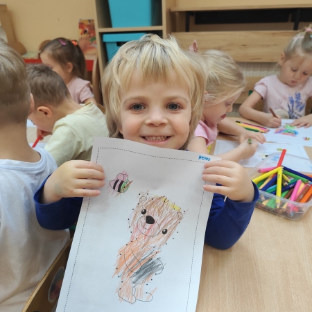 Fotografia kolorowa. Chłopiec i jego praca plastyczna.