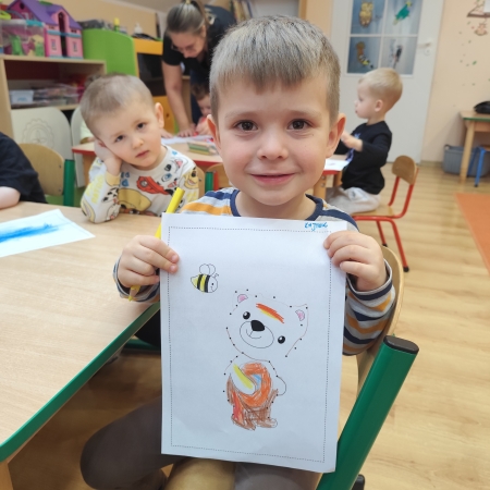 Fotografia kolorowa. Chłopiec i jego praca plastyczna.