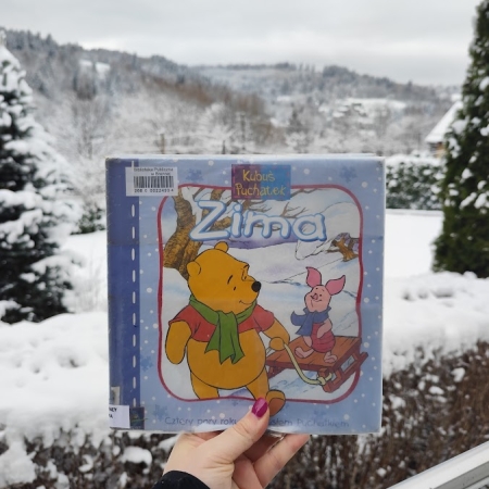 Fotografia kolorowa. Okładka książki na tle zaśnieżonej Brennej. 