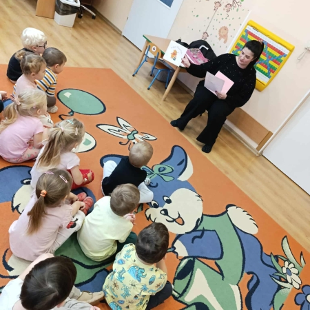 Fotografia kolorowa. Bibliotekarka robi dzieciom misiowy quiz. 