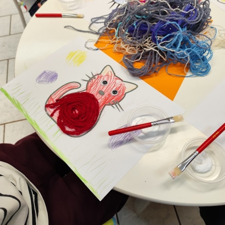 Fotografia kolorowa. Dzieci wykonują prace plastyczne we wnętrzu filii w Górkach Małych.