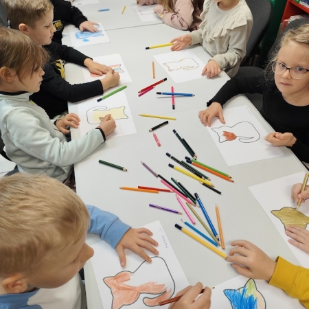 Fotografia kolorowa. Dzieci wykonują prace plastyczne we wnętrzu filii w Górkach Małych.