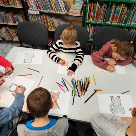 Fotografia kolorowa. Dzieci wykonują prace plastyczne we wnętrzu filii w Górkach Małych.
