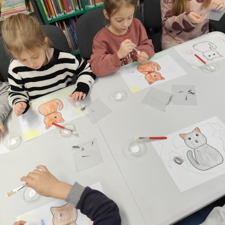 Fotografia kolorowa. Dzieci wykonują prace plastyczne we wnętrzu filii w Górkach Małych.