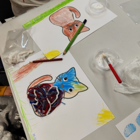 Fotografia kolorowa. Dzieci wykonują prace plastyczne we wnętrzu filii w Górkach Małych.