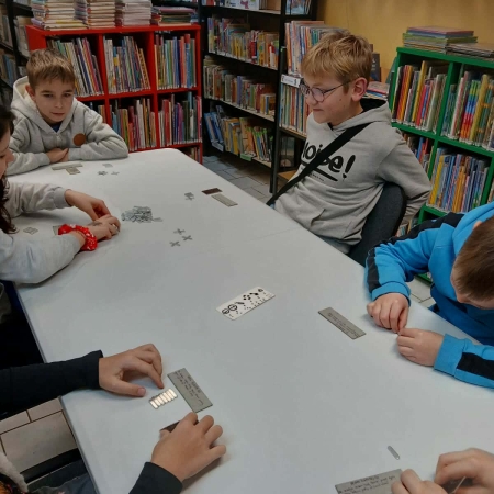 Fotografia kolorowa. Uczestnicy mikołajkowego planszogrania we wnętrzu filii w Górkach Małych.