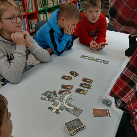 Fotografia kolorowa. Uczestnicy mikołajkowego planszogrania we wnętrzu filii w Górkach Małych.
