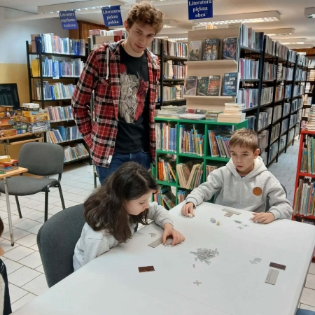 Fotografia kolorowa. Uczestnicy mikołajkowego planszogrania we wnętrzu filii w Górkach Małych.