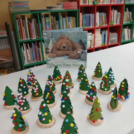 Fotografia kolorowa. Prace plastyczne dzieci i okładka książki "Święta pana Misia", w tle biblioteka w Górkach Małych. 